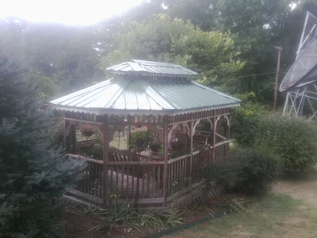 Green metal roof on a backyard gazebo surrounded by garden beds in Muscoda