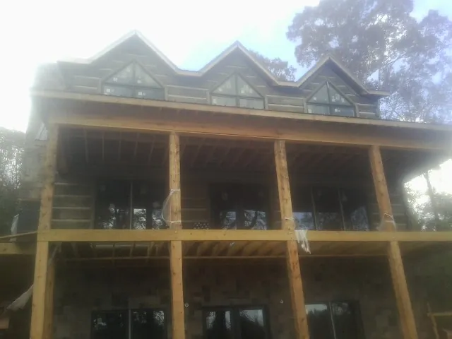 Dormers and porch framing on a large log home under construction — Roof Coating work by our crew in Muscoda