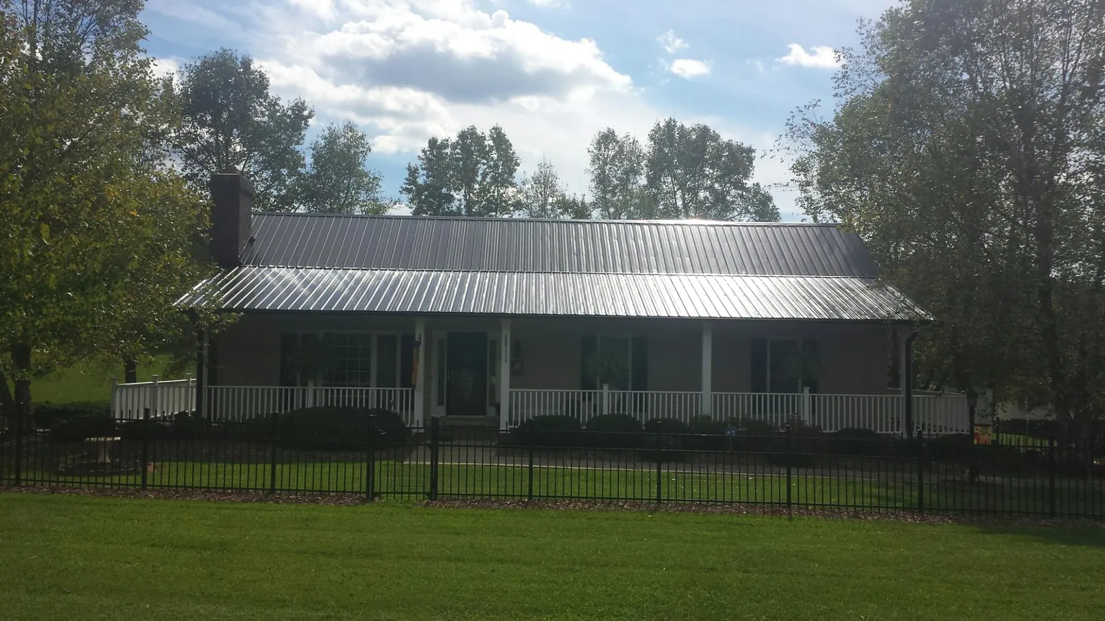 Gray metal roof on a brick ranch with a full width front porch — Gutter Guard Installation work by our crew in Muscoda