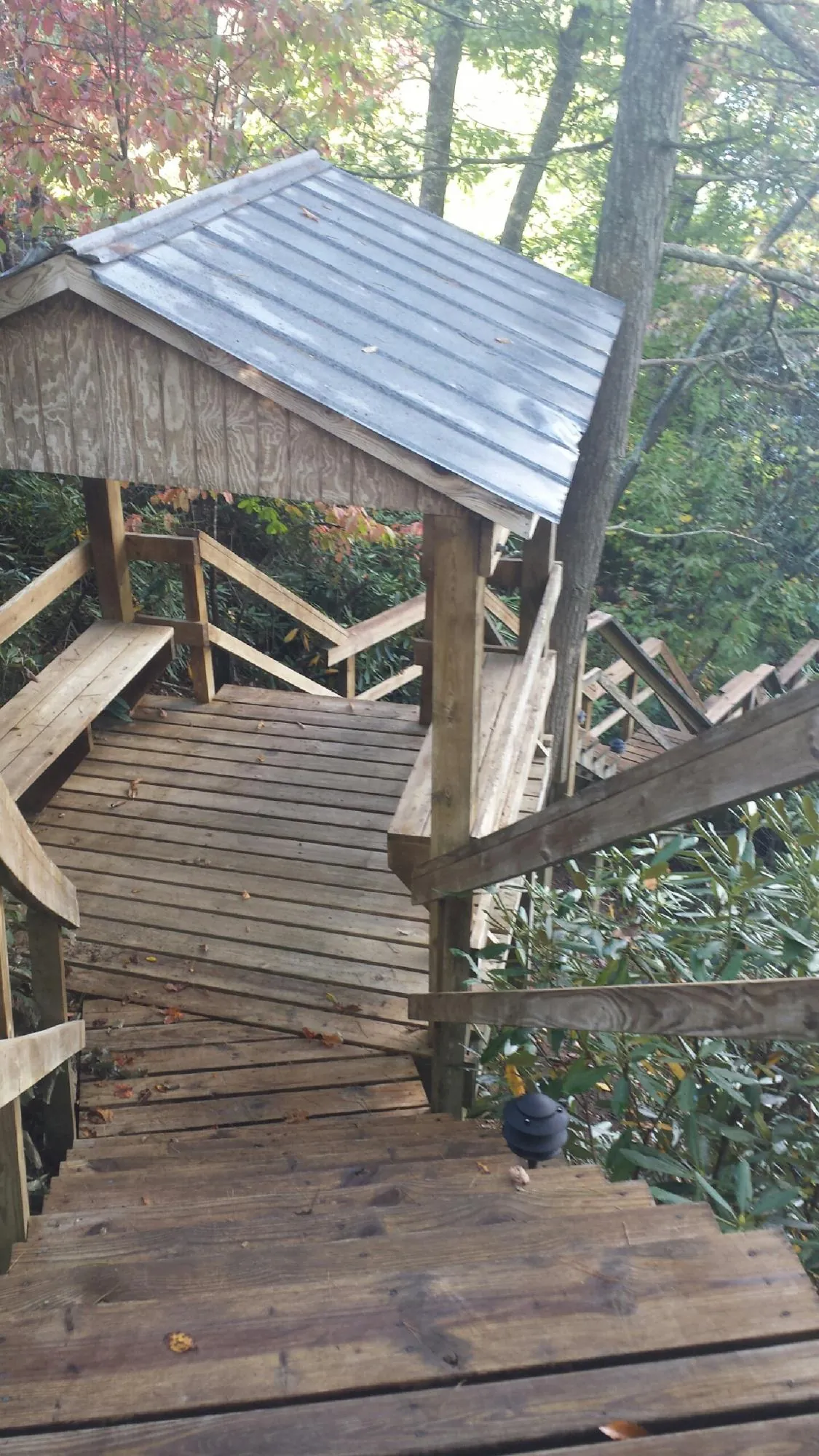 Metal roofed shelter over wooden steps on a wooded walkway — Skylight Repair & Installation work by our crew in Muscoda