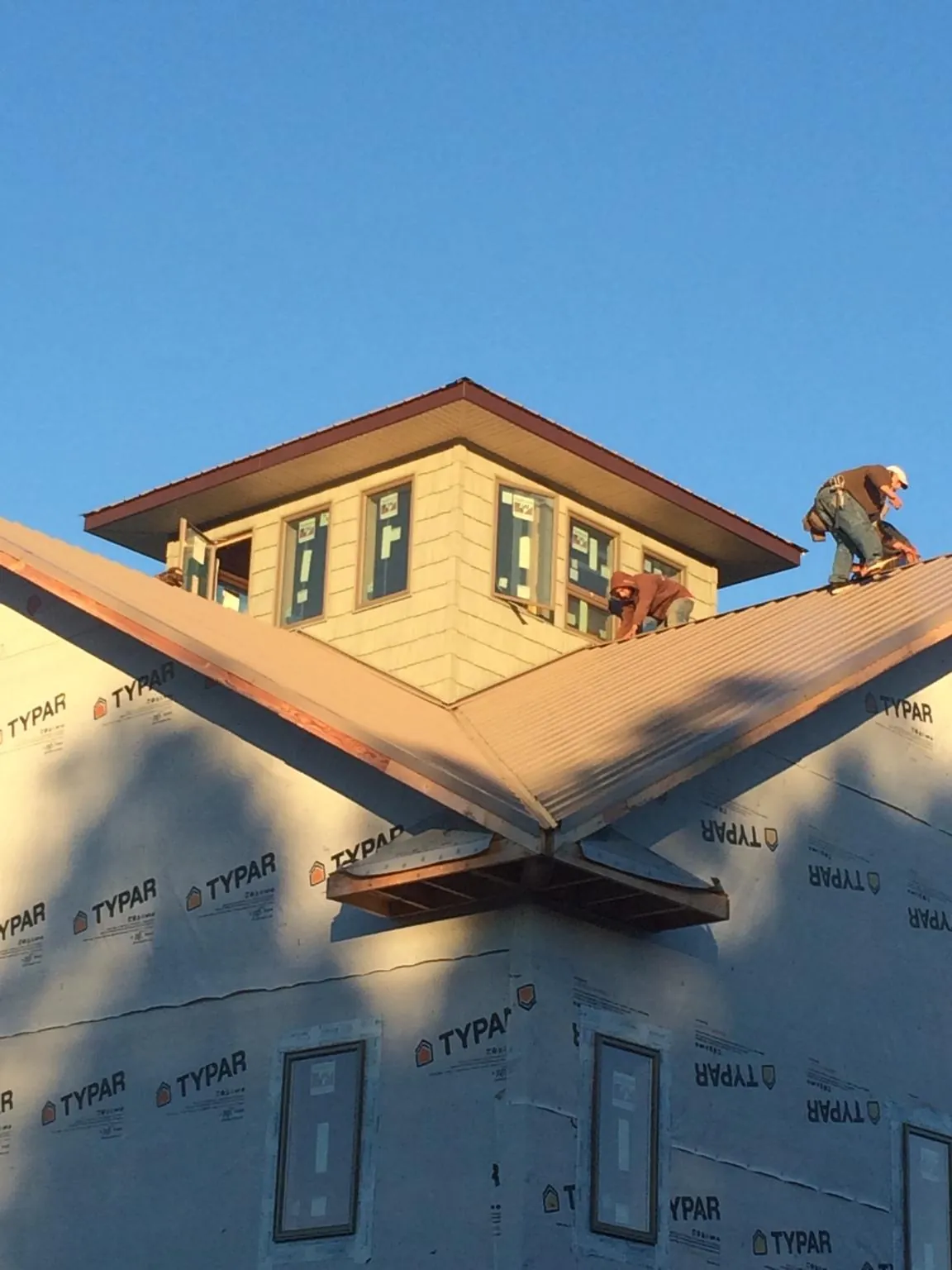 Roofers working around a rooftop cupola on a new metal roof at sunset — Roof Waterproofing in Muscoda by Roofing Brothers